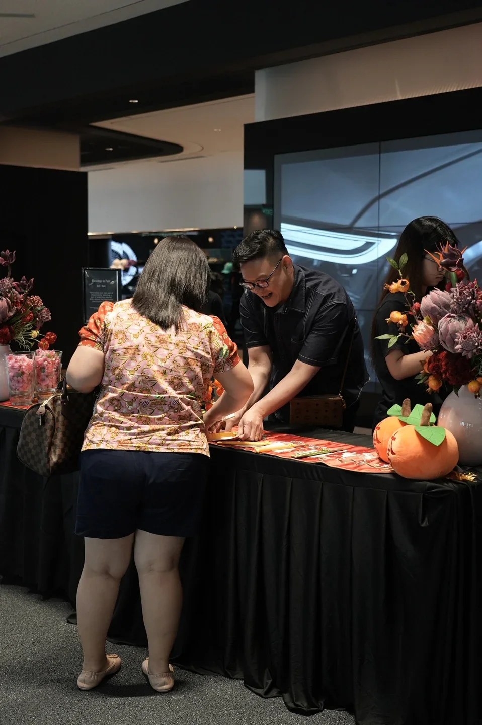 A host and guests gathered around a festive keepsake counter in a Mercedes-Benz showroom.